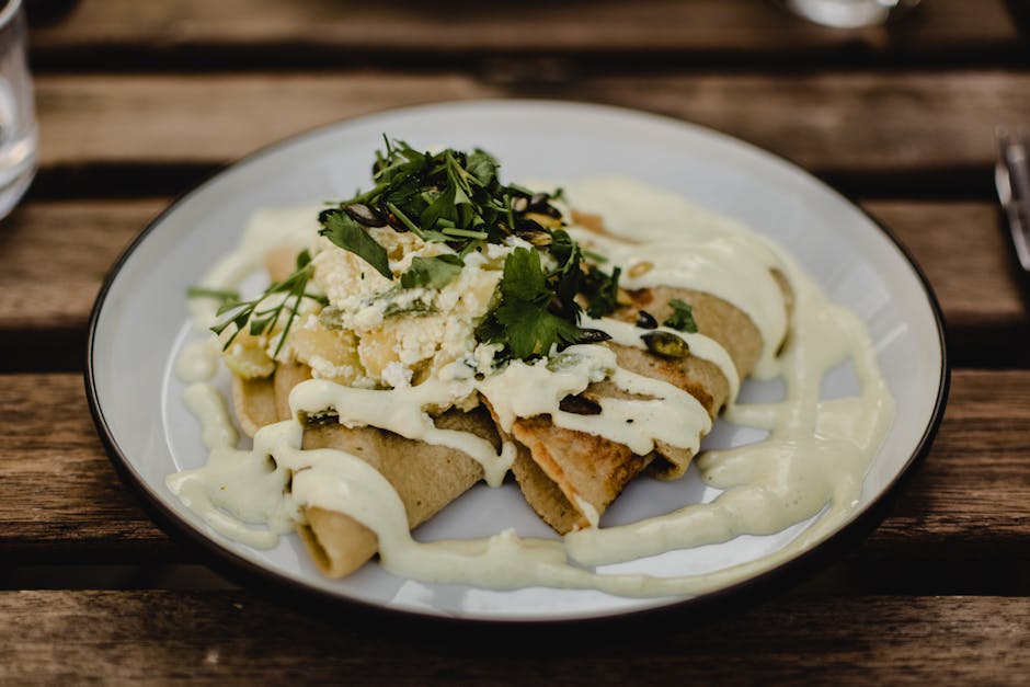 Freshly prepared pancakes topped with herbs and creamy sauce on a wooden table setting.