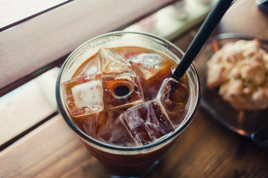 Chilled iced coffee in a glass with ice cubes and a black straw, perfect for a hot day.